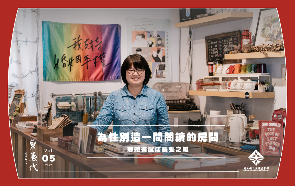 店長之維站在書店吧檯內部，後方掛著大大的彩虹旗，塑造性別友善的氛圍。